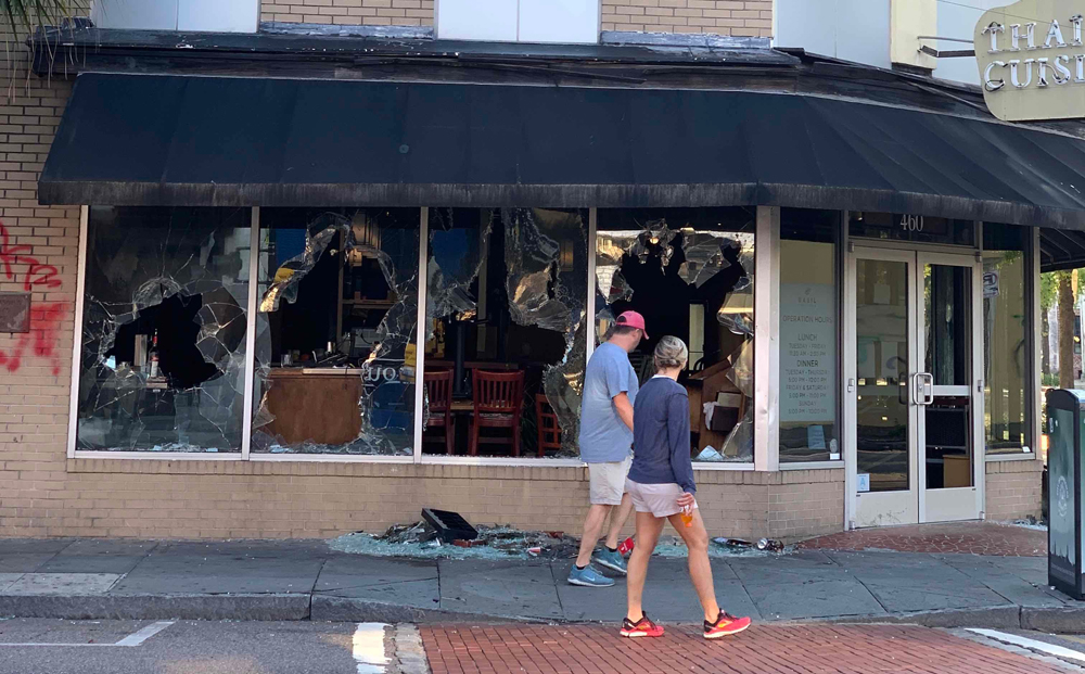 Passersby look at the damage to the windows of Basil Thai Cuisine on King Street in downtown Charleston on May 31. The damage occurred during social unrest the night of May 30 after the death of George Floyd, a black man, at the hands of Minneapolis police on May 25. (Photo/Shawnda Poynter)