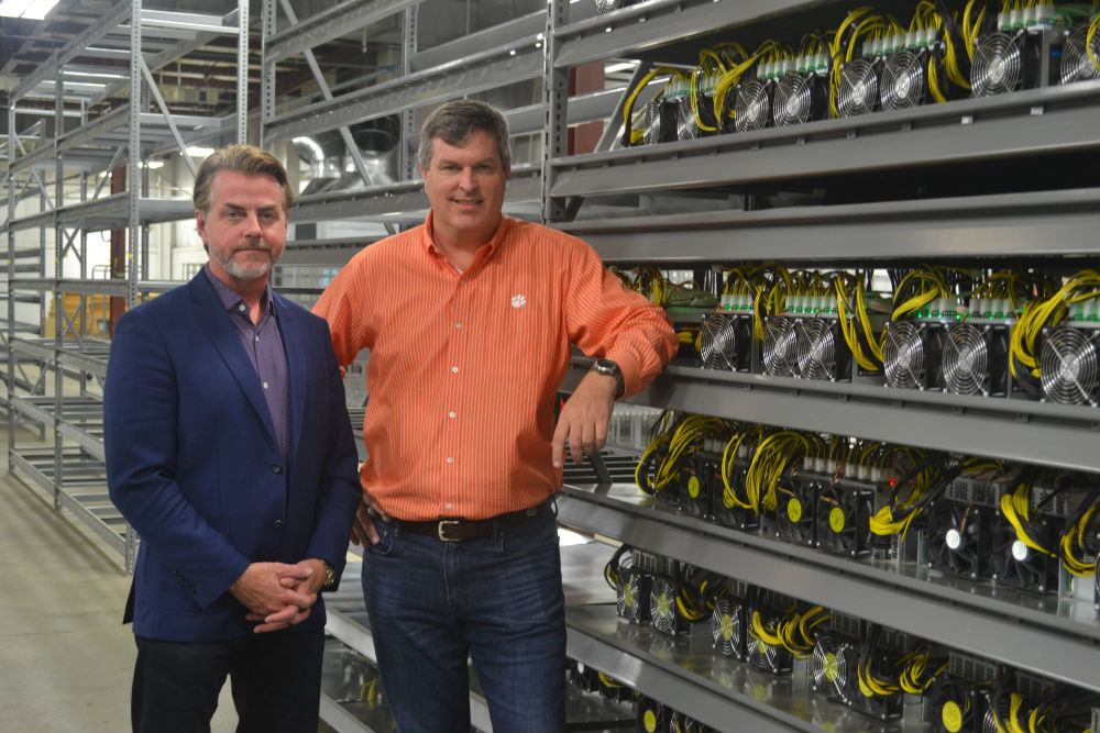Michael Bolick, left, and David Pence, two of the managing directors of Treis Blockchain LLC, stand by one of what eventually will be a warehouse full of racks of cryptocurrency mining servers. (Photo/Ross Norton)