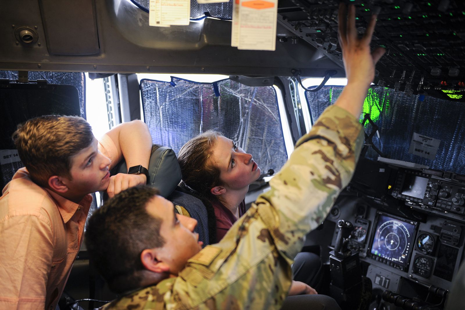 Senior Airman Ulises Zamora (center), a crew chief assigned to the 437th Aircraft Maintenance Squadron, explains some of the controls used on a C-17 Globemaster III to interns Aleric Stell (left) and Emma McBride. (Photo/Senior Airman Thomas T. Charlton for the Air Force)