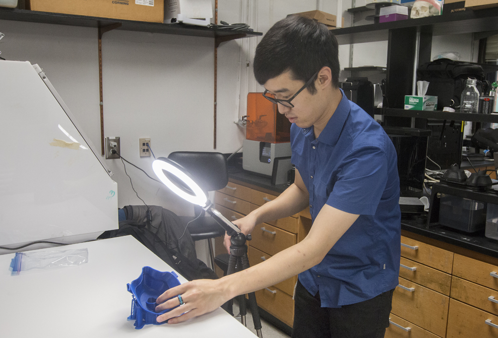 Joshua Kim inspects a protective mask created using 3D printing technology. He and a team of designers went through four different prototypes before the Self-Assembly Filter for Emergencies Cartridge System was finalized. (Photo/Provided)