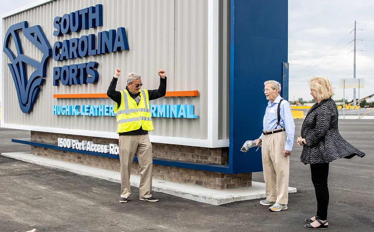 S.C. Ports Authority President and CEO Jim Newsome celebrates with Hugh K. Leatherman and Jean Leatherman as the senator breaks a bottle of champagne across the sign of the new namesake terminal. (Photo/Kim McManus)