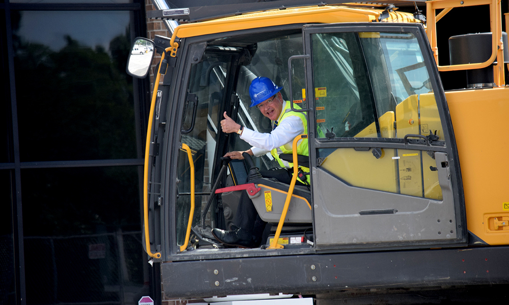 While Charleston Mayor John Tecklenburg seems completely comfortable behind the keyboard of a piano, he also seemed to relish this moment at the controls of an excavator on May 29 in West Ashley. (Photo/Patrick Hoff)