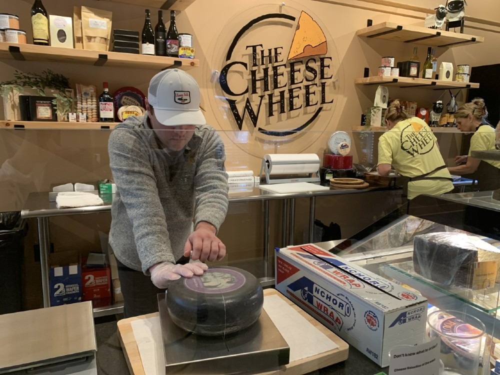 Michael Davitt slices into a new wheel of cheese at The Cheese Wheel, which opened on Augusta Street. (Photo/Krys Merryman)