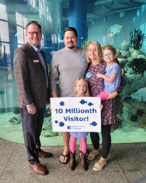 President and CEO of the S.C. Aquarium Kevin Mills celebrates the aquarium‰Ûªs 10 millionth visitors: Nic and Stacia D‰ÛªAngelo, and their daughters, Emery and Aubrey. 