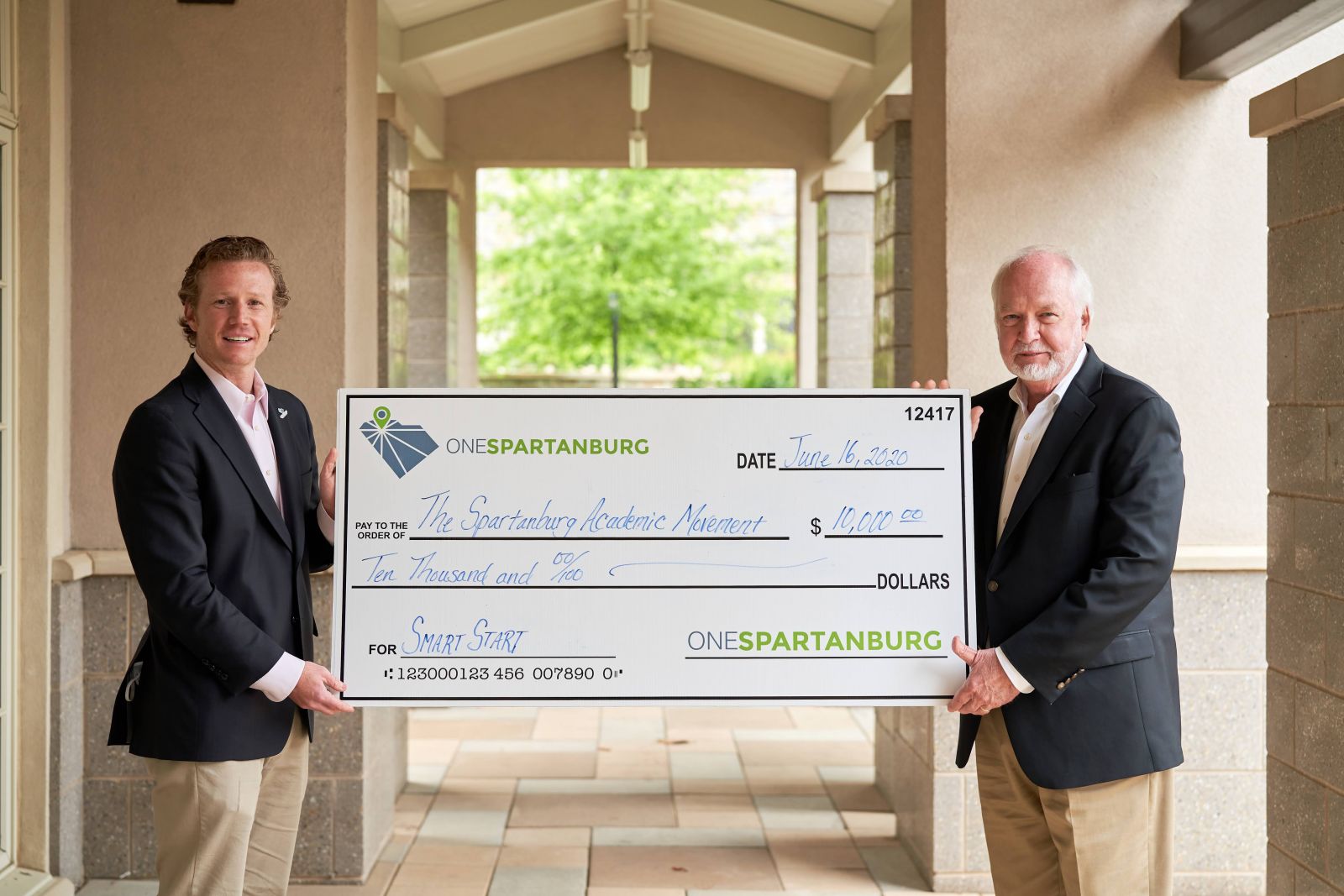 John Stockwell, executive director of the Spartanburg Academic Movement and OneSpartanburg CEO post with check. (Photo/Provided)
