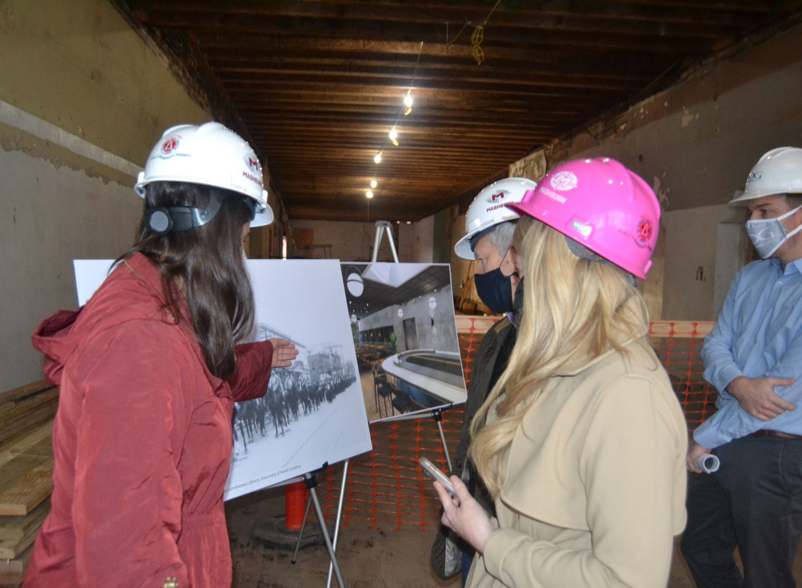 Janie Campbell (far left) points out details in historic photographs to a group including Columbia-area developer Scott Middleton (center, in black mask). Campbell researches details to make sure historic preservation projects accurately reflect time periods and qualify for applicable local, state and federal tax credits. (Photo/Melinda Waldrop)