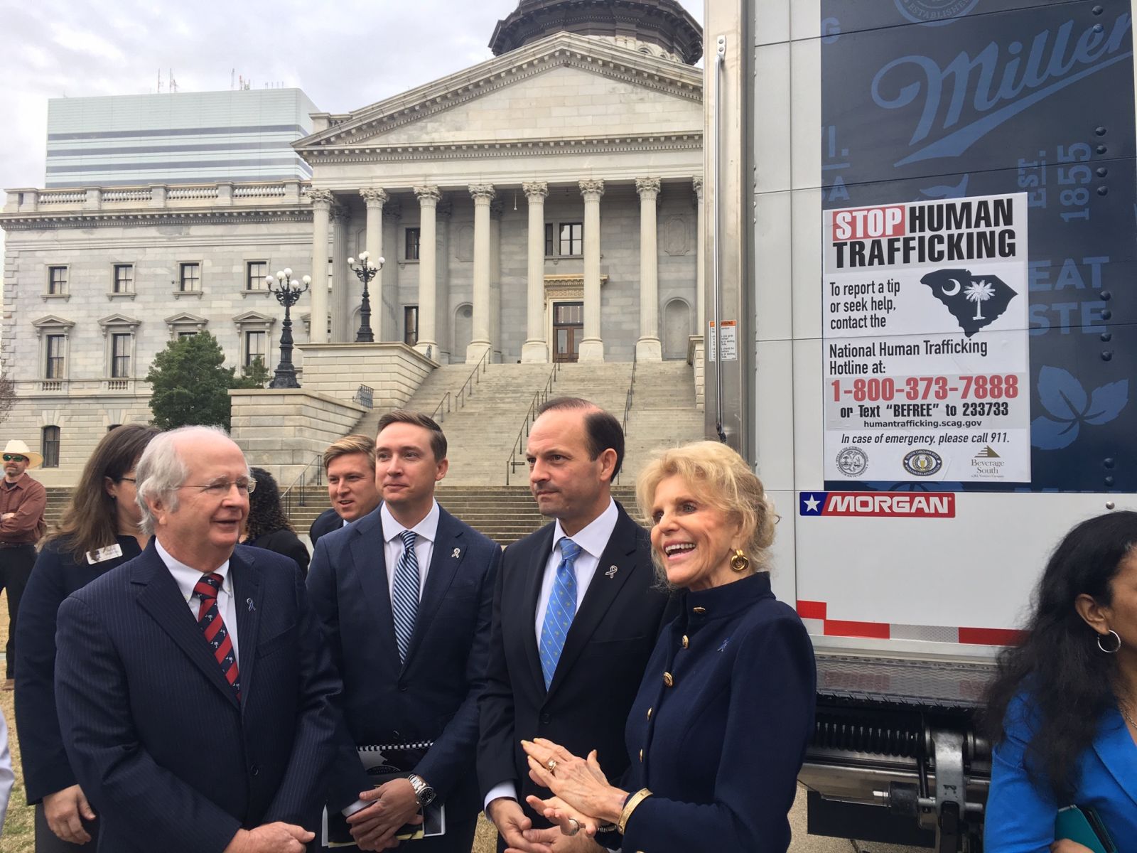 Peggy McMaster (from right), S.C. Attorney General Alan Wilson and S.C. Beer Wholesalers Association Executive Director Lance Boozer pose by a beer truck displaying the National Human Trafficking Hotline number. (Photo/Renee Sexton)