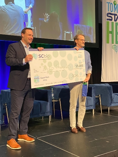 James Chappell (left), CEO and president of SCBIO, awards the $5,000 pitch prize to Scott Pancoast, founder and CEO of Zylo Therapies. (Photo/Jenny Peterson) (the check awarding presentation)